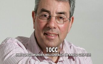 Sänger 10cc in lila Hemd auf grauem Hintergrund