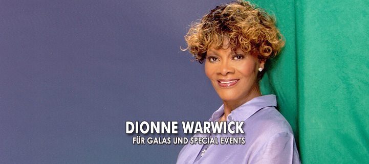 Sängerin Dionne Warwick vor blau grünem Hintergrund in einer lila Bluse