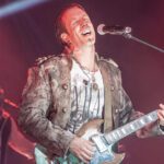 Sänger Johanns Erben spielt E-Gitarre auf der Bühne und singt in ein Mikrofon 