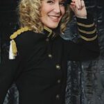 Sängerin Linda Jo Rizzo in Captain Outfit vor schwarzer Wand
