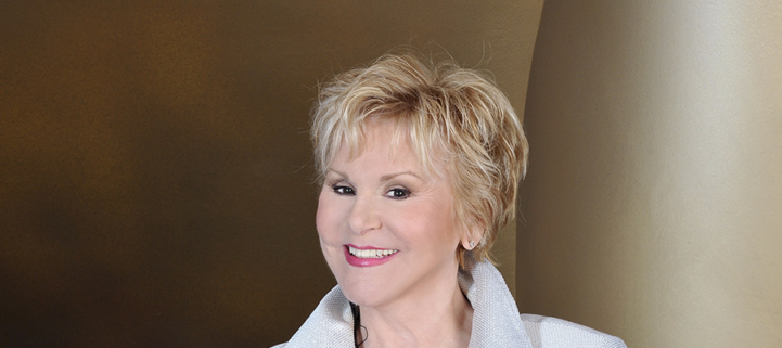 Sängerin Peggy March in silberner glänzender Jacke auf gold grauem Hintergrund