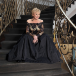 Sängerin Peggy March in schwarz goldenem Kleid auf einer schwarzen Treppe