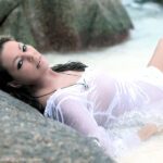 Sängerin Sandra in einer kleinen Bucht liegend mit einer Welle auf sie zukommend